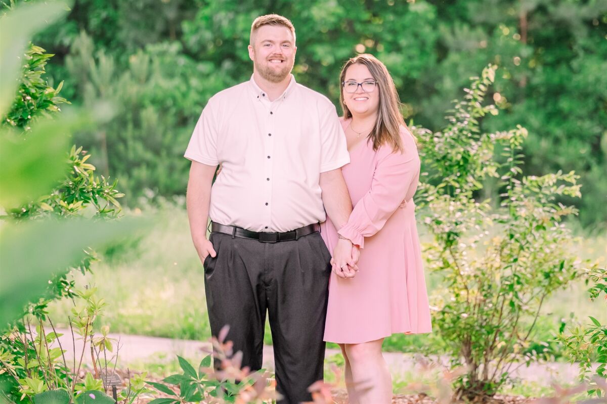 A happy couple hold hands both in pink in the Airlie Gardens wedding venue with big smiles