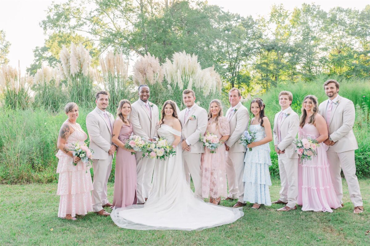A bride and groom stand with their wedding party at sunset during their Rose Hill Estate Wedding with everyone in pink