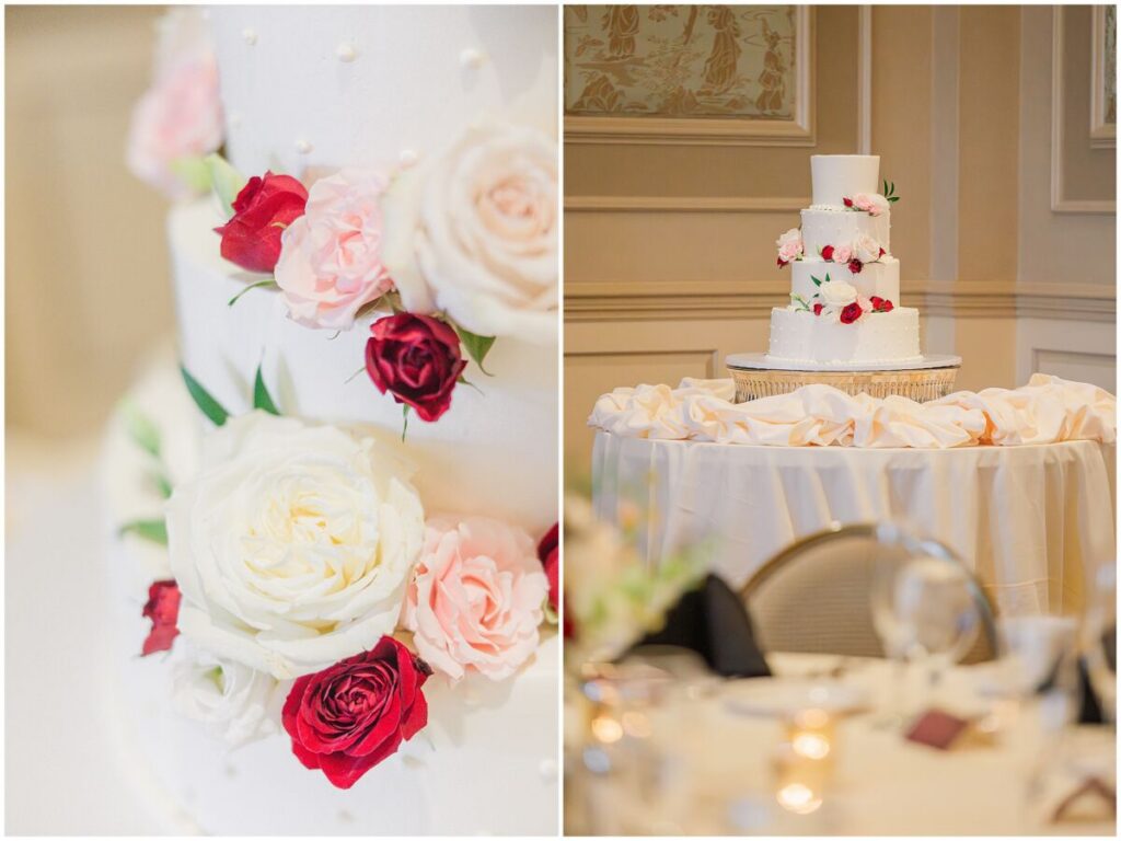 A yummy four tiered white wedding cake with pink, red, and white florals on it