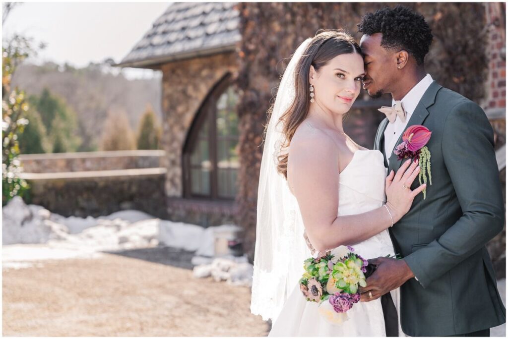 A loving couple nuzzling on each other during their February wedding