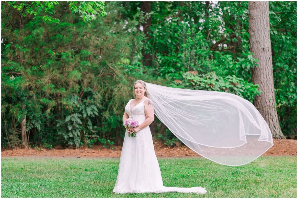 A blushing blonde bride on her wedding day with pops of purple on her wedding day at Terra Blooms Farm by JoLynn Photography