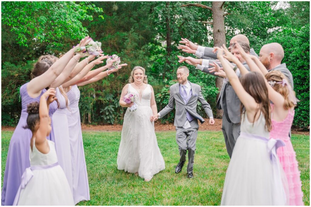 A beautiful wedding party during a summer wedding at Terra Blooms Farm in a vivid green garden by JoLynn Photography