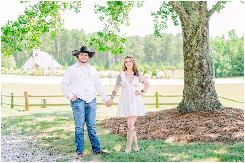 A happy groom in a cowboy hat enjoying his Pavilion at Carriage Farm engagement by JoLynn Photography with his glowing bride to be