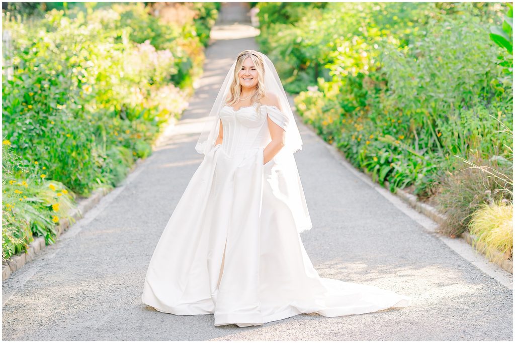 A glowing blonde bride in a beautiful wedding down with pockets during her Duke Gardens bridal portraits session by JoLynn Photography