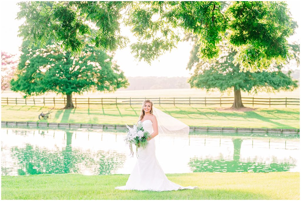 A glowing Rose Hill Estate bridal portrait of a beautiful blonde bride during a summer sunset overlooking the water during a dreamy session by JoLynn Photography